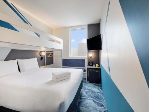 a hotel room with a large white bed and a window at ibis Budget Auckland Airport in Auckland