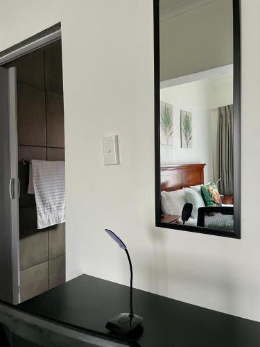 a mirror sitting on a table in a bedroom at Lapaleholo Guesthouse in Phuthaditjhaba