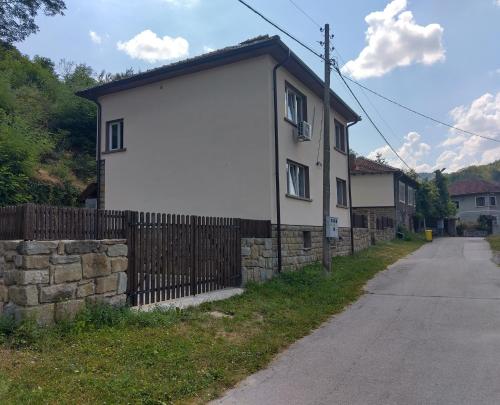 a white house with a fence next to a road at Къща Владислав in Radevtsi