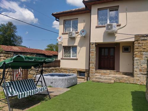 a yard with a chair and an umbrella in front of a house at Къща Владислав in Radevtsi