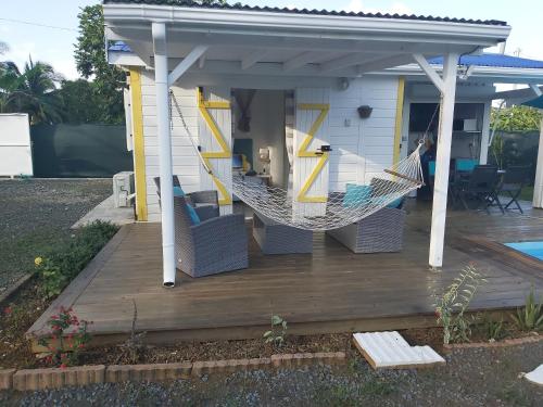 a hammock on a deck in front of a house at Bungalow chic à Sainte-Rose + piscine. in Sainte-Rose