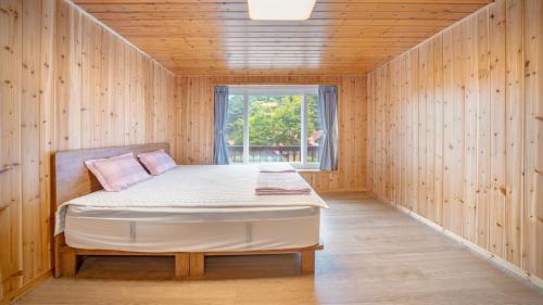 a bed in a wooden room with a window at Gapyeong Humantown Pension in Gapyeong