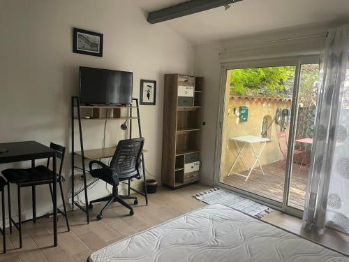 a living room with a television and a desk and a sliding glass door at Studio Oustaou à Château Gombert in Marseille