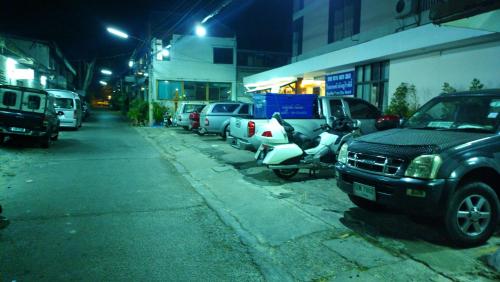 a parking lot with cars and a scooter parked on a street at Hua Hin Euro City Hotel in Hua Hin