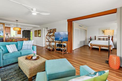 a living room with blue furniture and a bedroom at Maui Eldorado Condo J123 in Kaanapali