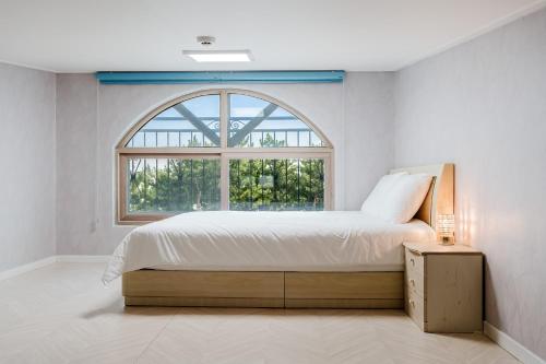 a bedroom with a bed and a large window at Samcheok The Ggeullim Pension in Samcheok