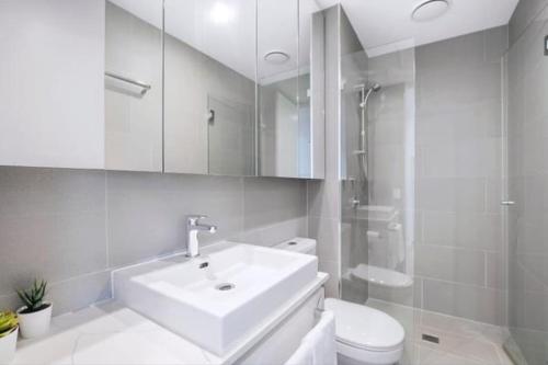 a white bathroom with a sink and a toilet at Bright CBD 2 bedroom resort-style escape in Brisbane