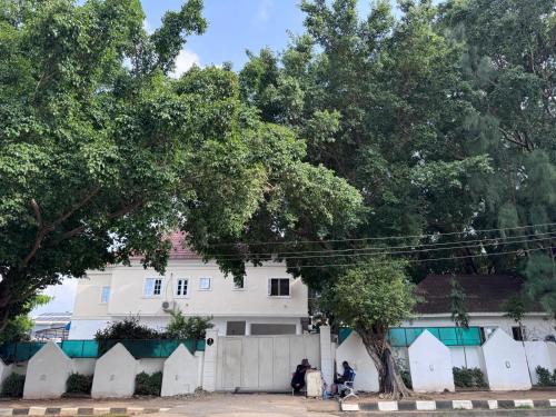 a white house with a white fence and trees at Hotel House 1 in Abuja