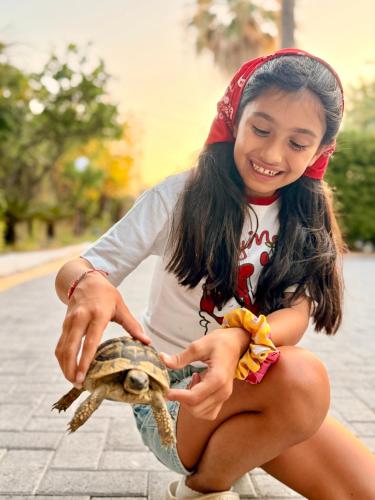 a young girl holding a turtle on the street at Villa Pami in Almiros Beach