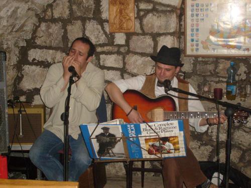 two men are singing and a man with a guitar at Böne Vendégház és Borozó in Tokaj