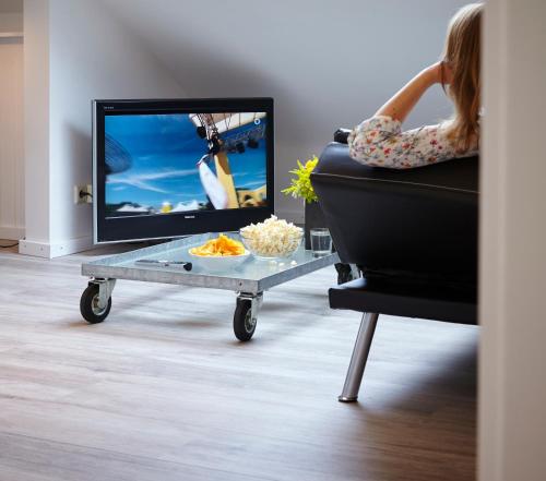a woman sitting on a couch with a television on a cart at Ferienwohnung Schwarz in Mayen