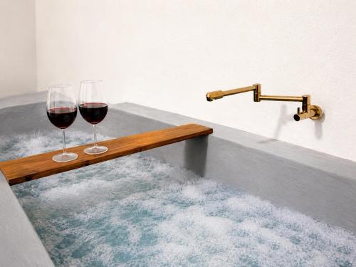 two glasses of red wine sitting on a bath tub at Raya Beach Studios in Maresias