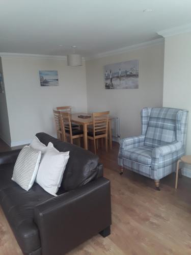 a living room with a couch and a table and chairs at isleofmanholidayapartment in Douglas