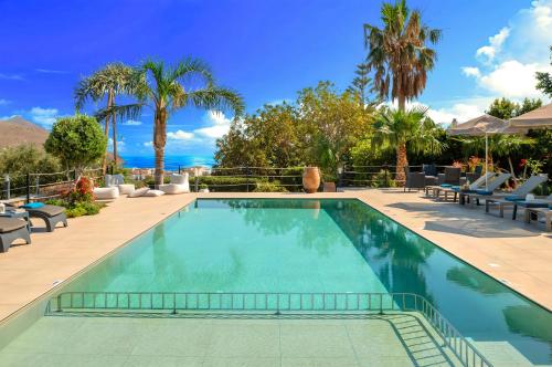 a swimming pool in a resort with palm trees at Cretan Dream Villa in Georgioupolis