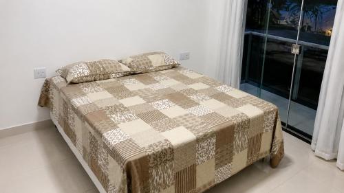 a bed with a blanket and pillows in a bedroom at Paraíso Escarpas do Lago 1 - Capitólio in Capitólio