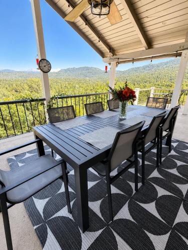 a wooden table and chairs on a porch with a view at Mountain Daddies Boutique Bed & Breakfast near Yosemite - Fresh Homemade Breakfast Included in Oakhurst