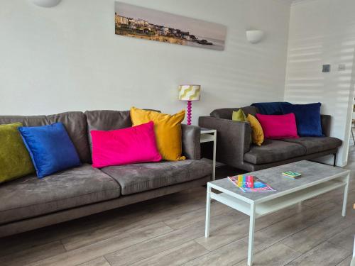 a living room with a couch with colorful pillows at Seaside House Broadstairs by the Beach with Parking in Broadstairs
