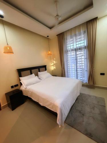 a bedroom with a large white bed and a window at Cozynest nungwi in Nungwi