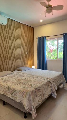 a bedroom with a bed with blue curtains and a window at Villas Pura Vida - Mango in Puntarenas