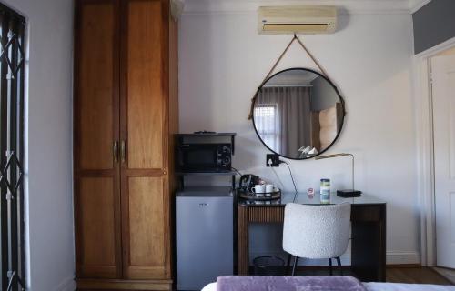 a room with a table and a mirror and a refrigerator at Blue Crane Luxury Accommodation in Welkom