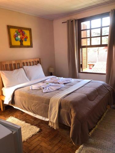 a bedroom with a large bed with a window at Aconchego Mineiro in Visconde De Maua