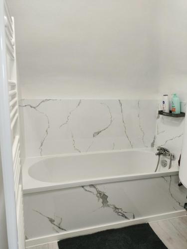 a white bathroom with a white tub and marble walls at Max-El's Home in Geispolsheim