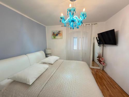 a bedroom with a large white bed with a chandelier at Apartman Luna in Šibenik
