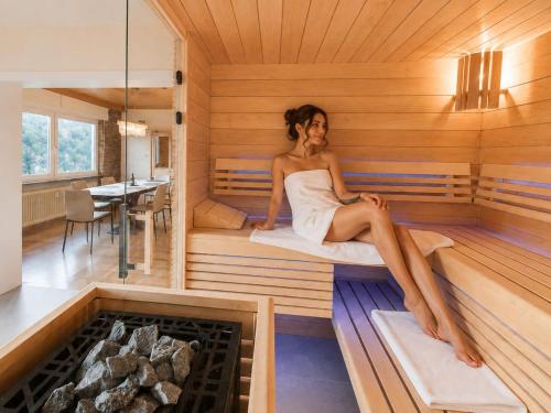 a woman sitting on a bed in a sauna at PMC Traumblick Suite & Spa - Whirlpool & Sauna in Bad Ems
