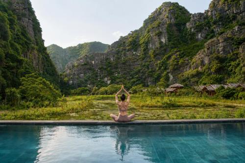 a woman doing yoga on the edge of a swimming pool at Karsia Retreat Ninh Binh in Ninh Binh