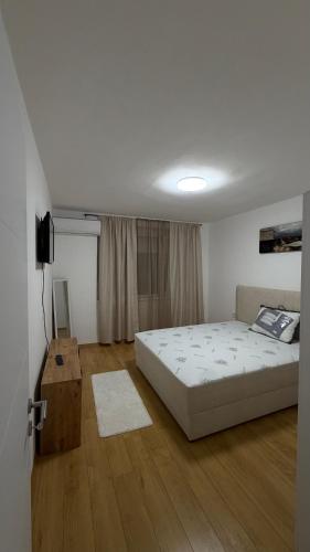 a bedroom with a white bed and a wooden floor at Urban Apartment Karpoš in Skopje