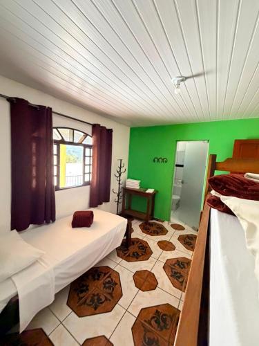 a room with two beds and a green wall at Pousada Caminho das Aguas in Lindóia