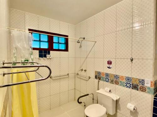 a bathroom with a toilet and a shower with a window at Hotel Canto do Rio Maresias in Maresias