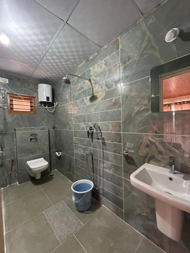 a bathroom with a shower and a sink and a toilet at Spatika Villa in Madikeri