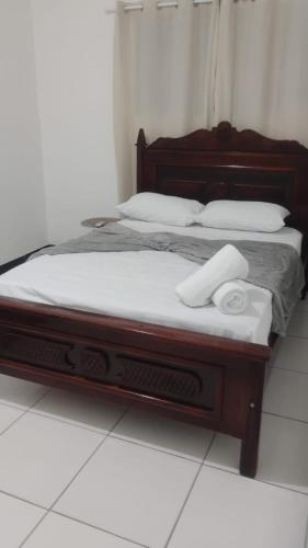 a bed with a wooden frame with two towels on it at Pousada dos Marujos in Pipa