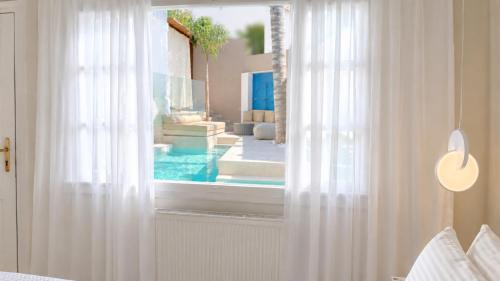 a bedroom with a view of a pool through a window at Villa Kallergi Athena in Loutra