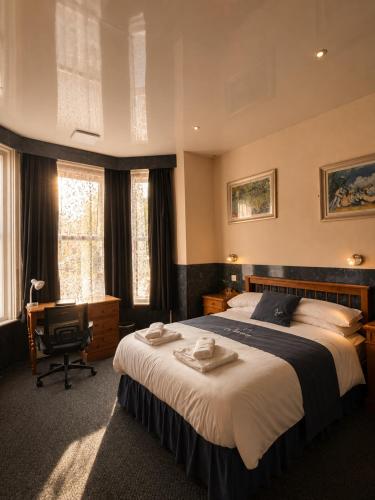 a bedroom with a large bed and a desk and window at Argyle Lodge Self Catering Guest House in Southampton