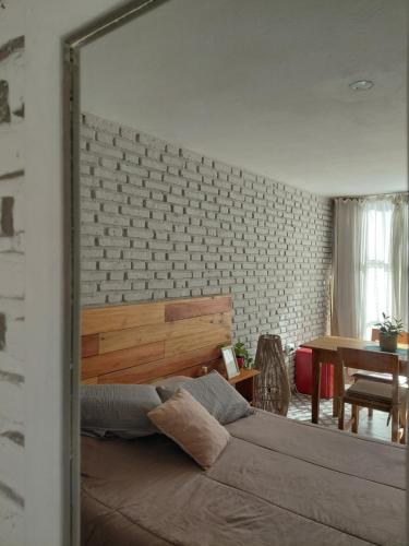 a bedroom with a bed and a brick wall at Casa Olivia Habitación Privada in Alta Gracia