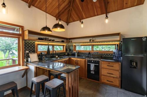 a kitchen with wooden cabinets and a black refrigerator at Carenero Hills - Beach and Surf Bungalows in Bocas Town