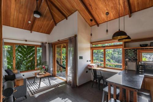a kitchen with wooden ceilings and windows and a table with chairs at Carenero Hills - Beach and Surf Bungalows in Bocas Town