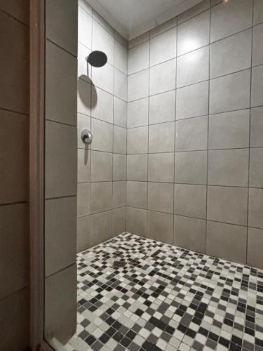 a bathroom with a shower with a black and white checkered floor at BoniM Guesthouse - aka Magisha Guesthouse in Nelspruit