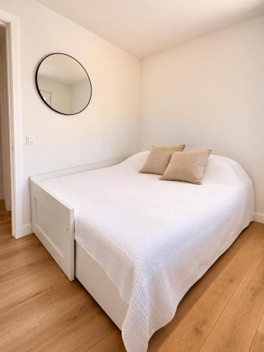 a bedroom with a white bed with a mirror on the wall at La Cachette du Lac-Douce parenthèse en famille près du lac & piscine in Lacanau