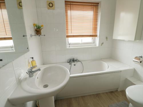 a white bathroom with a tub and a sink at Ty Haf in Holyhead