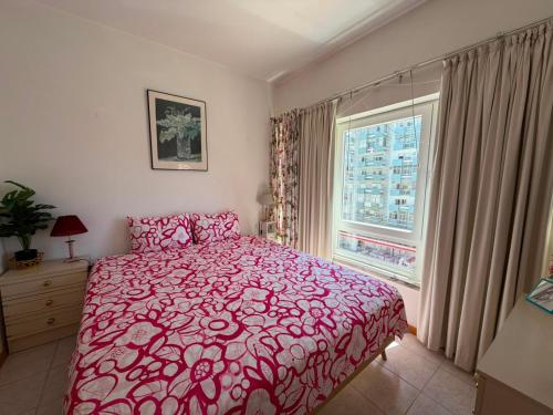 a bedroom with a red bed and a window at Atlantic Romantic Caparica Flat in Costa da Caparica