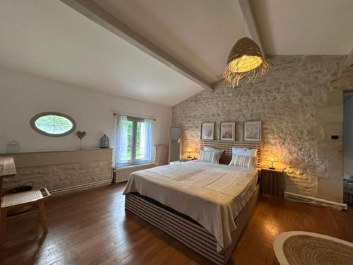 a bedroom with a large bed and a stone wall at Logis de Rault in Sainte-Ouenne