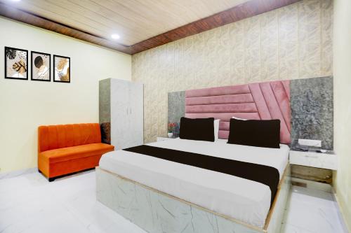 a bedroom with a bed and an orange chair at HOTEL O RAJDHANI in Kānpur