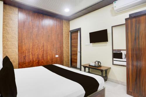 a bedroom with a bed and a tv on the wall at HOTEL O RAJDHANI in Kānpur