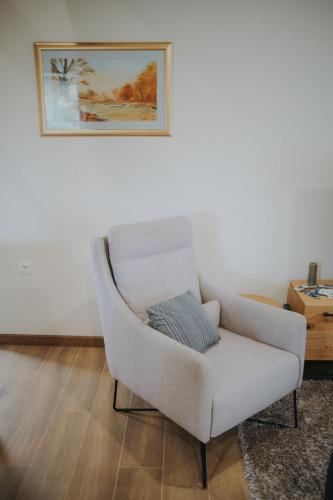 a white chair in a living room with a picture on the wall at Kuća za odmor Back to Bašić in Mandičevac