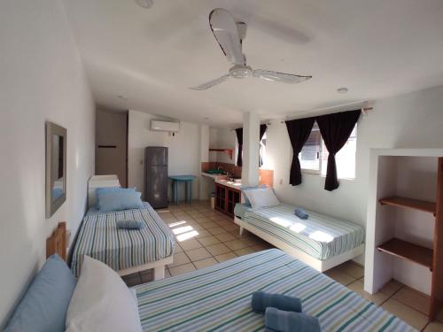 a living room with two beds and a ceiling fan at Hotel Papaya Surf in Puerto Escondido