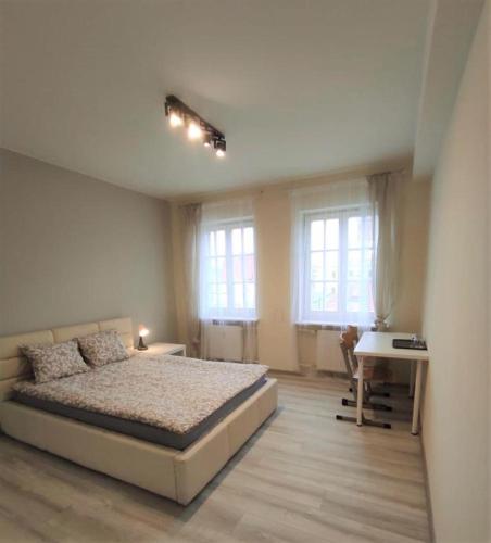 a bedroom with a bed and a desk and two windows at Rynek 5 in Poznań