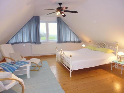 Un dormitorio con una cama blanca y un ventilador de techo. en Ella's Ferienwohnung, en Roikier